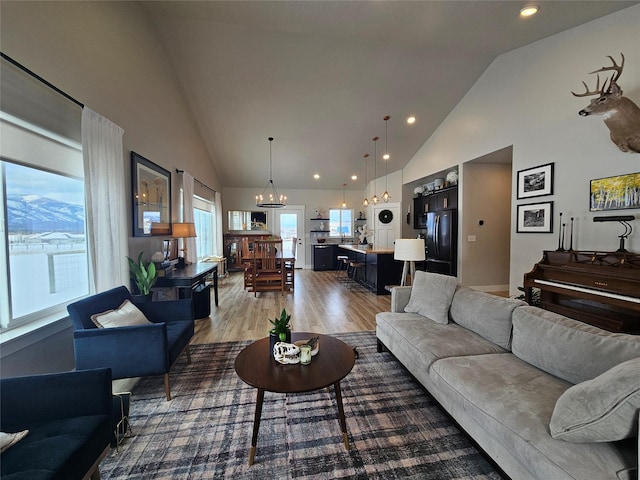 living room featuring an inviting chandelier, high vaulted ceiling, wood finished floors, and recessed lighting