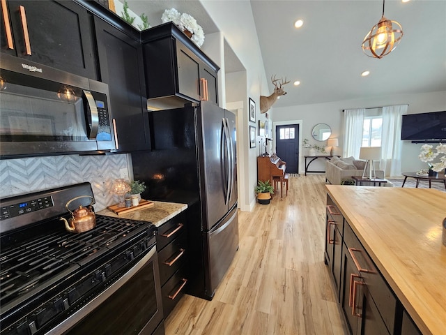 kitchen with open floor plan, stainless steel appliances, butcher block counters, and dark cabinets