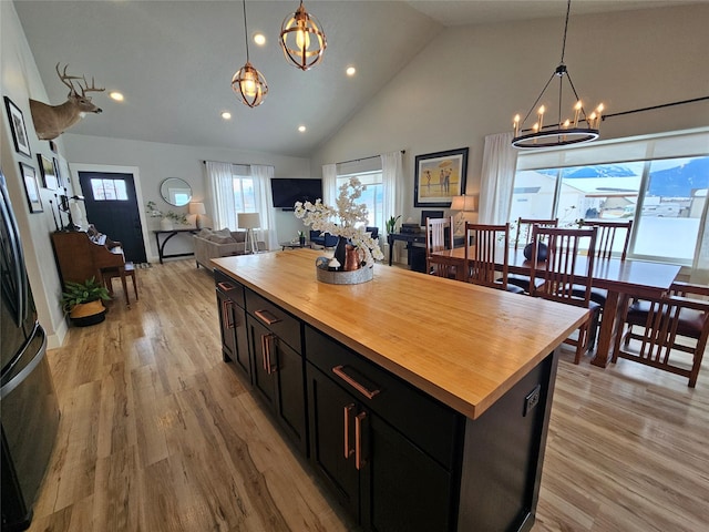 kitchen with open floor plan, butcher block countertops, light wood finished floors, and dark cabinetry