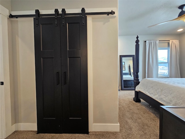 bedroom with carpet floors, a barn door, and baseboards