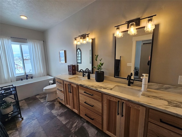 bathroom featuring a soaking tub, a sink, toilet, and double vanity