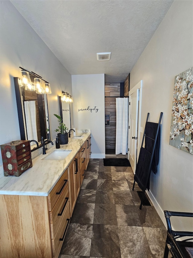 bathroom featuring visible vents, a sink, baseboards, and double vanity