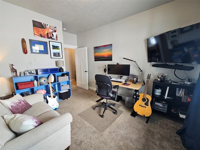 carpeted home office featuring a textured ceiling and baseboards