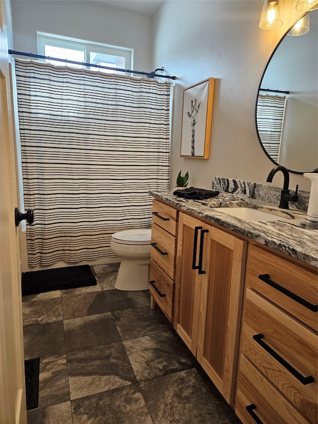 bathroom with a shower with curtain, stone finish floor, vanity, and toilet