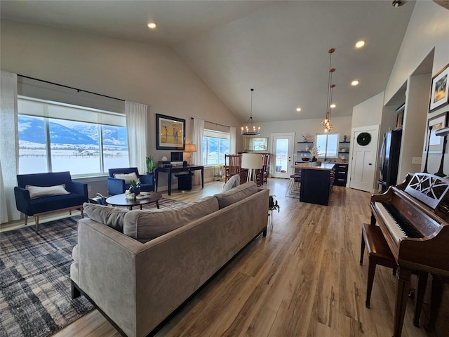 living room with high vaulted ceiling, recessed lighting, a notable chandelier, and wood finished floors