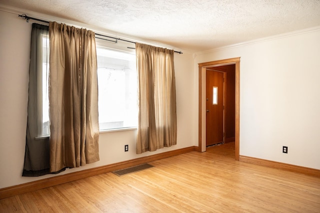 spare room with a wealth of natural light, visible vents, a textured ceiling, and light wood finished floors