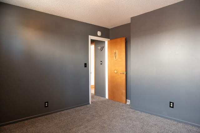 carpeted spare room with baseboards and a textured ceiling