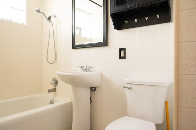 bathroom with shower / bathtub combination, a wealth of natural light, toilet, and tile walls