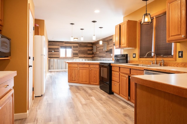 kitchen featuring black range with electric cooktop, a sink, light countertops, freestanding refrigerator, and decorative light fixtures