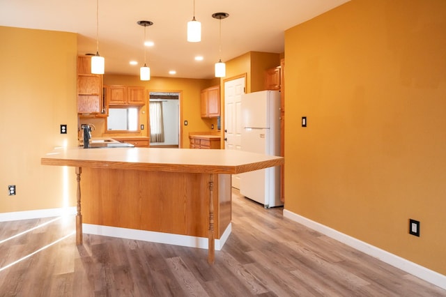 kitchen with freestanding refrigerator, a peninsula, light countertops, open shelves, and a sink