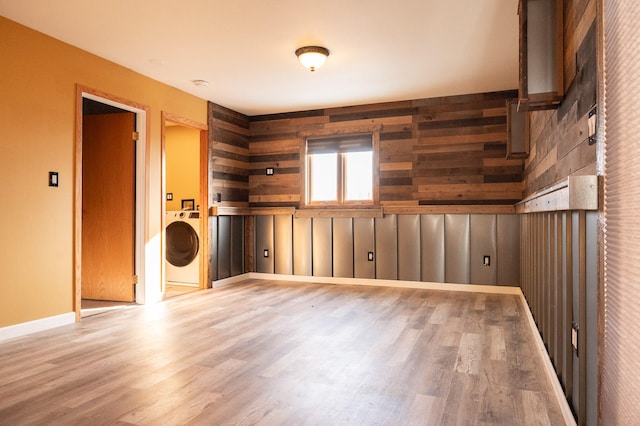 empty room with washer / clothes dryer, baseboards, and wood finished floors