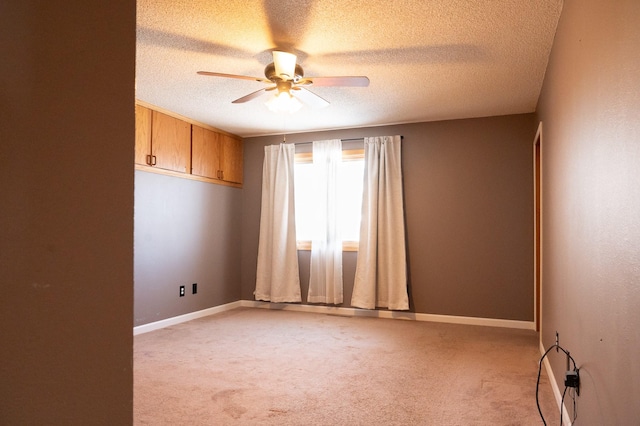 spare room featuring light carpet, baseboards, and a ceiling fan