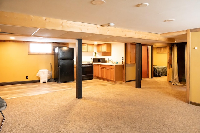 basement featuring freestanding refrigerator, light carpet, a sink, and baseboards