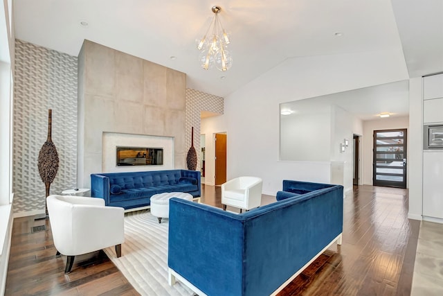 living area with dark wood-style flooring, a fireplace, visible vents, vaulted ceiling, and an inviting chandelier