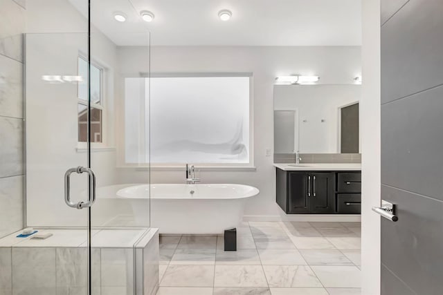 full bathroom with marble finish floor, a stall shower, a soaking tub, and vanity