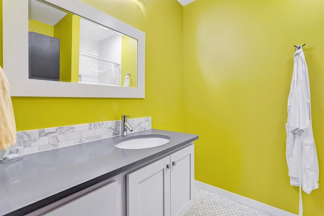 full bathroom with a tile shower, vanity, and baseboards