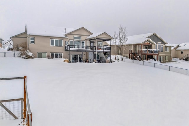 snow covered house with stairway and a wooden deck