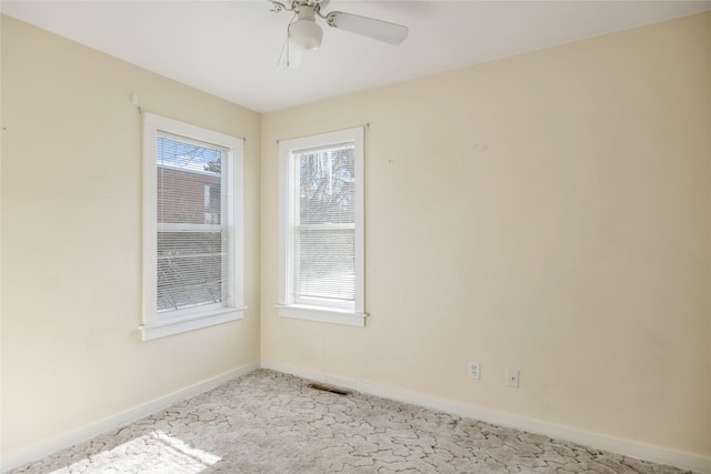 empty room featuring a ceiling fan, light carpet, visible vents, and baseboards