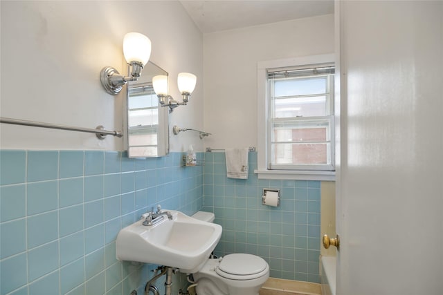 bathroom with wainscoting, a sink, toilet, and tile walls