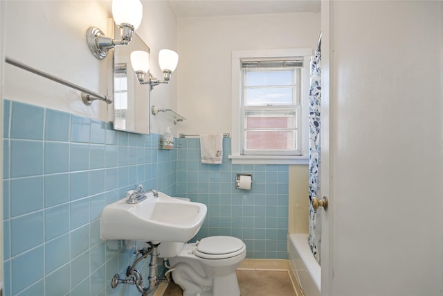 bathroom with tile walls, shower / bathtub combination with curtain, toilet, a sink, and a chandelier