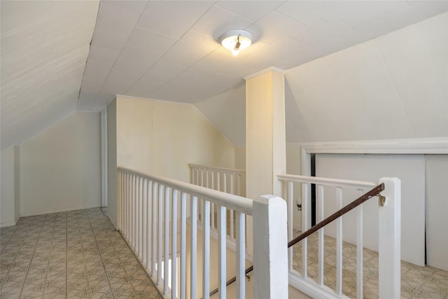 hallway with lofted ceiling and an upstairs landing