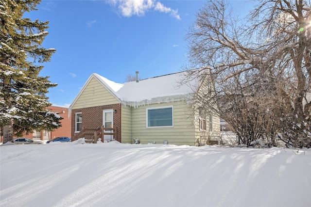 snow covered property featuring brick siding