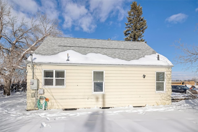 snow covered house featuring a shingled roof