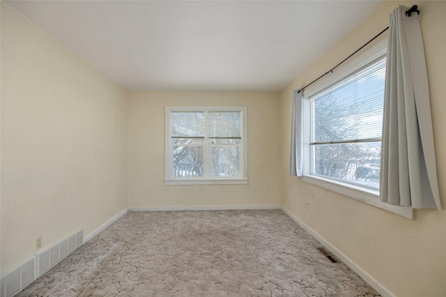 empty room featuring baseboards, visible vents, and light colored carpet