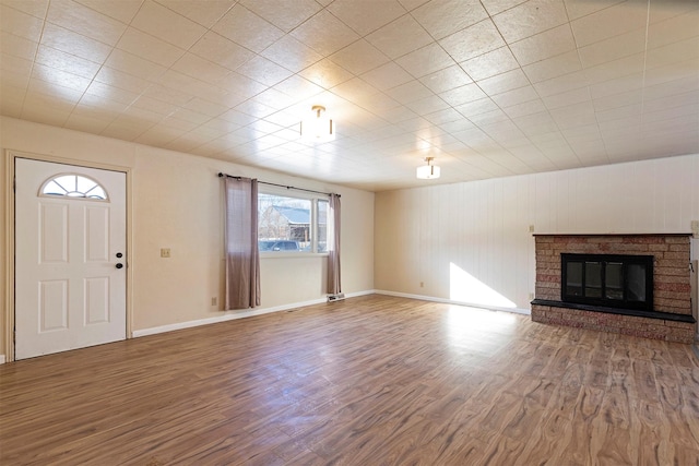 unfurnished living room with a fireplace, wood finished floors, and baseboards