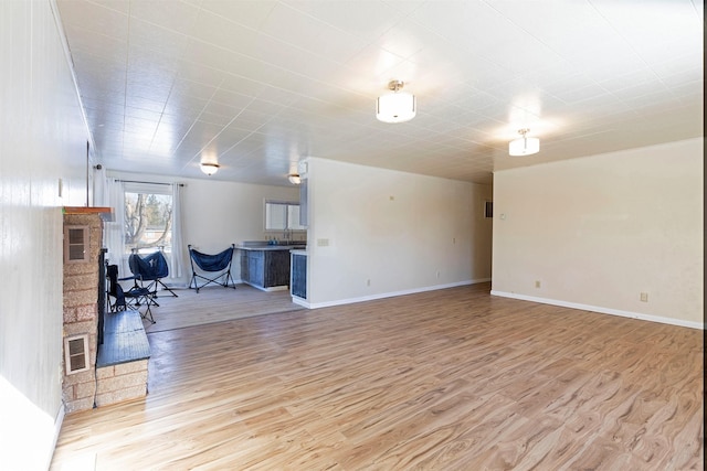 living room with a fireplace, wood finished floors, visible vents, and baseboards