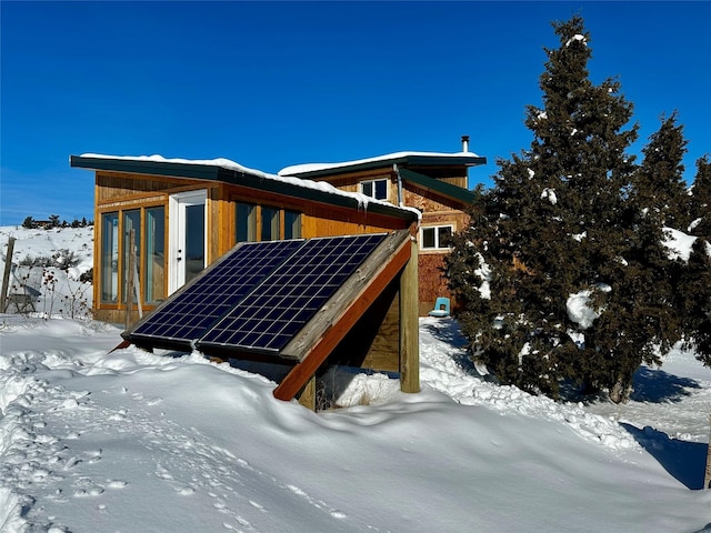 snow covered property featuring roof mounted solar panels