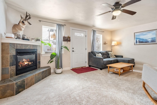 carpeted living area with baseboards, a ceiling fan, and a tile fireplace