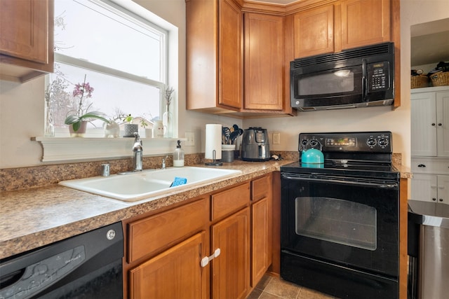 kitchen with brown cabinets, black appliances, light countertops, and a sink