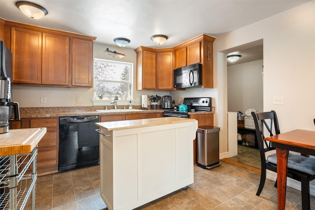 kitchen with light countertops, brown cabinetry, a sink, a kitchen island, and black appliances