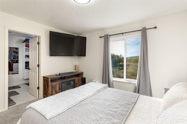 bedroom with a closet, a walk in closet, marble finish floor, and a textured ceiling