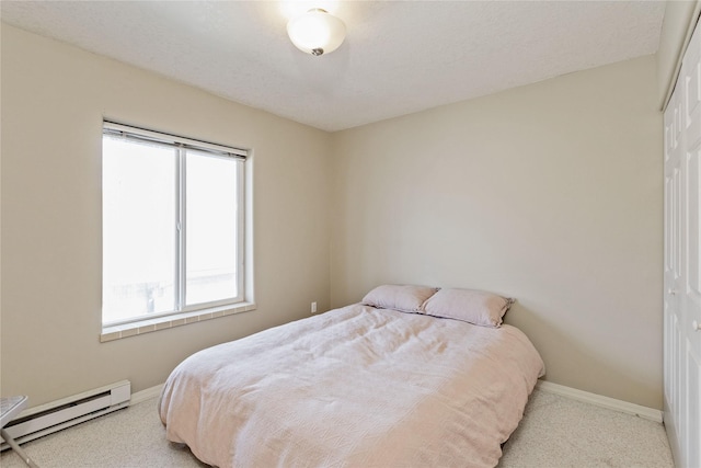 bedroom with light carpet, baseboards, baseboard heating, and a closet