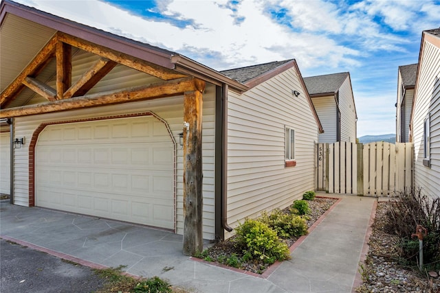 view of side of home featuring a garage and fence