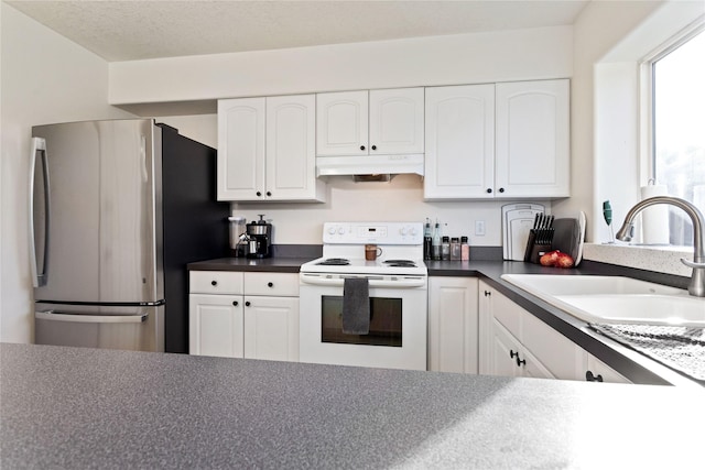 kitchen featuring freestanding refrigerator, white cabinets, white electric range, and a sink