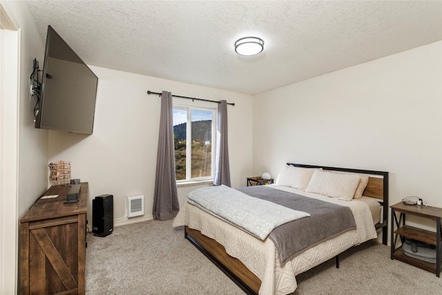 bedroom featuring light carpet, a textured ceiling, and visible vents