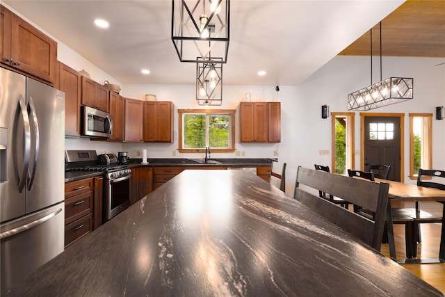 56 Nelson Dr, Rexford, MT 59930 - kitchen with brown cabinets, decorative light fixtures, stainless steel appliances, dark countertops, and a sink