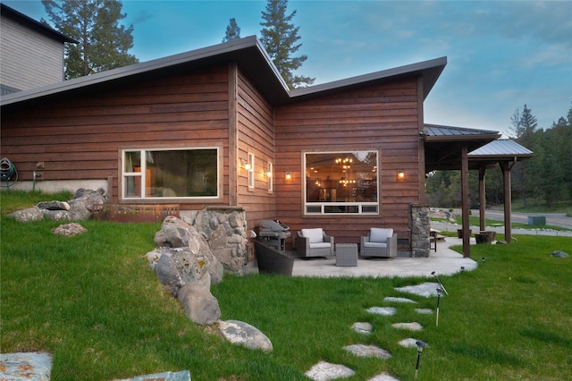 rear view of house featuring an outdoor hangout area, metal roof, a lawn, and a patio area