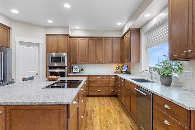 kitchen with stainless steel appliances, brown cabinets, and light wood finished floors