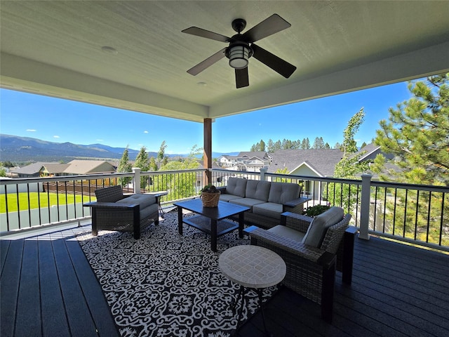 wooden deck with ceiling fan, a residential view, a mountain view, and an outdoor living space