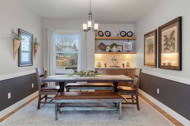 dining area with baseboards, an inviting chandelier, and wood finished floors