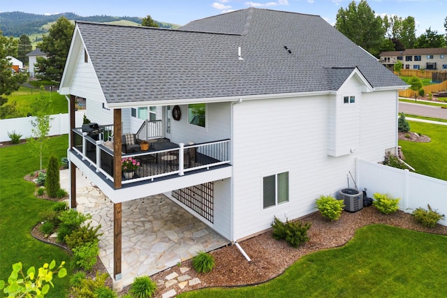 back of house with a deck, a yard, a shingled roof, and fence