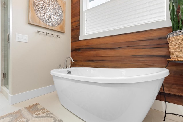 bathroom with wooden walls, a stall shower, a freestanding tub, and tile patterned floors