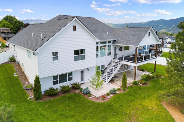 back of house featuring a lawn, a patio, stairway, roof with shingles, and a deck with mountain view