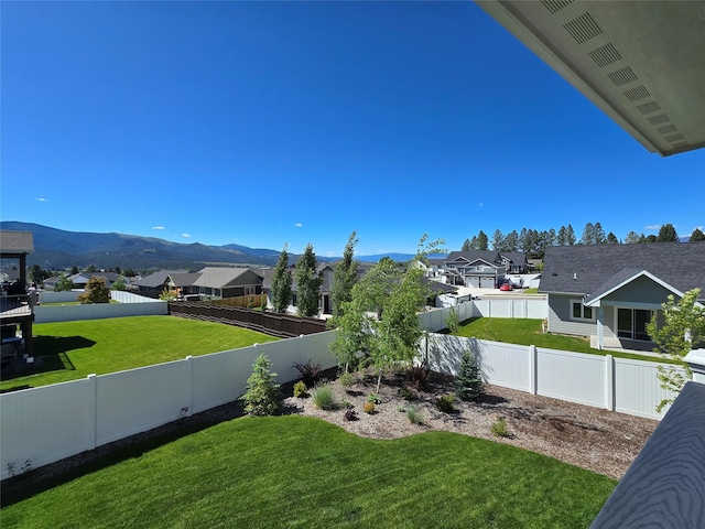 view of yard with a residential view, a fenced backyard, and a mountain view