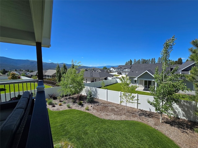 view of yard featuring a mountain view, a fenced backyard, and a residential view