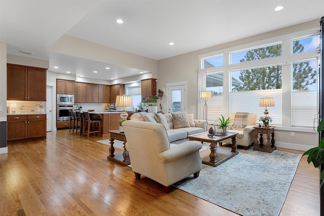 living area with recessed lighting, visible vents, and wood finished floors